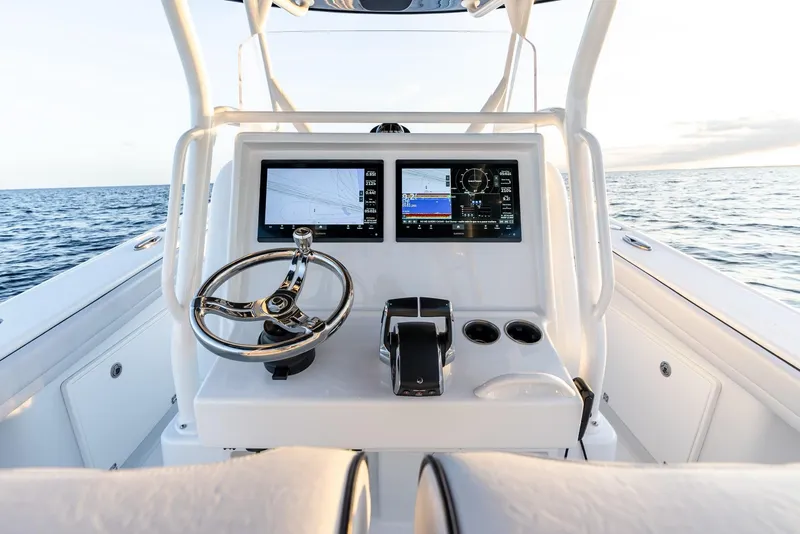 Slide: The Image of 2023 Yellowfin 34 boat dashboard with dual screens and steering wheel on open water. - 14