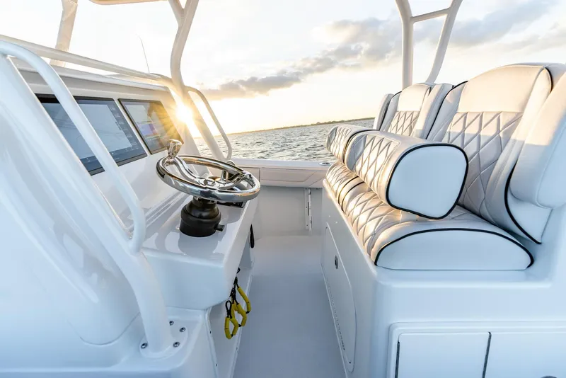 Slide: The Image of 2023 Yellowfin 34 boat interior with steering wheel and cushioned seating at sunset. - 16