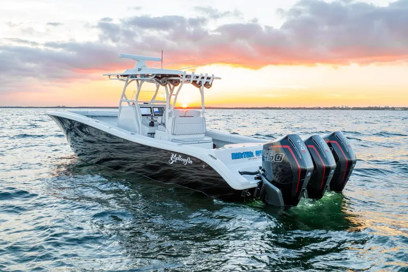 Slide: The Image of 2023 Yellowfin 34 boat on water at sunset with triple outboard engines. - 2