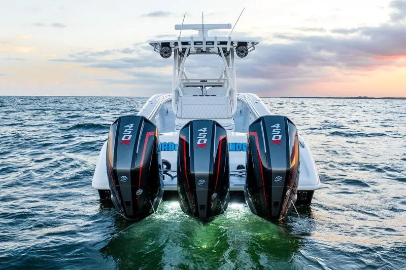 Slide: The Image of 2023 Yellowfin 34 boat with triple outboard engines on open water at sunset. - 9