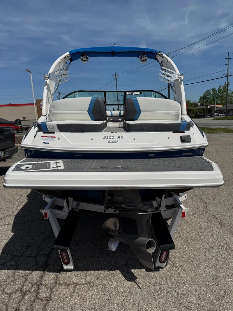 Slide: The Image of 2017 Regal 2300 RX Surf boat, rear view, parked on pavement under clear sky. - 3