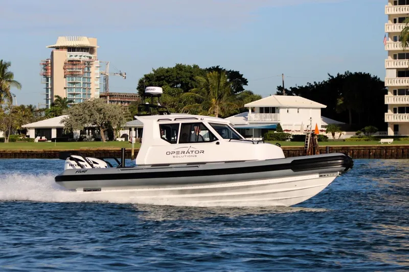 Slide: The Image of 2022 Fluid Watercraft Patrol 880 Cabin cruising on a sunny day near waterfront buildings. - 5