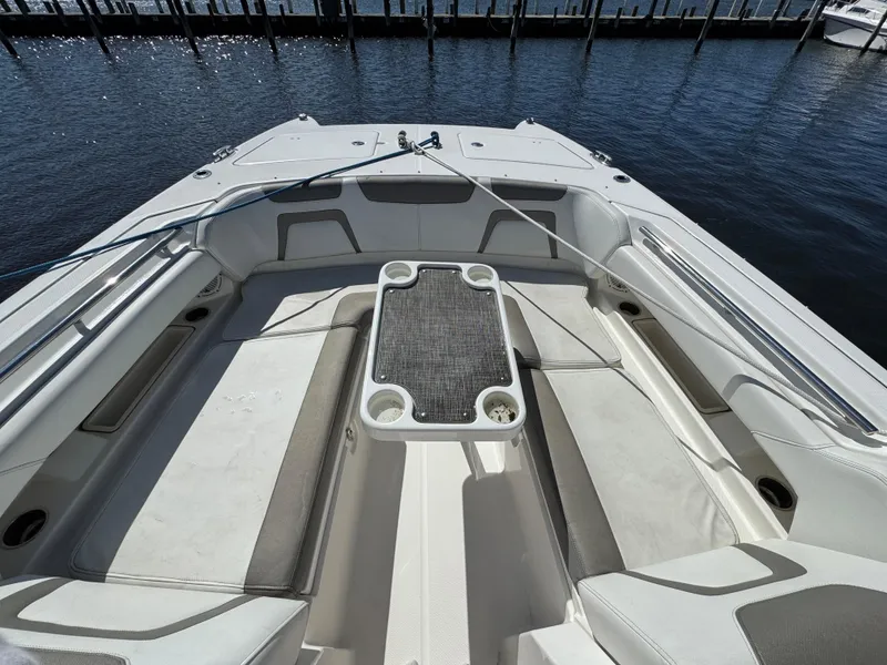 Slide: The Image of 2020 World Cat 280 DC-X boat interior with seating and table, docked by the water. - 7