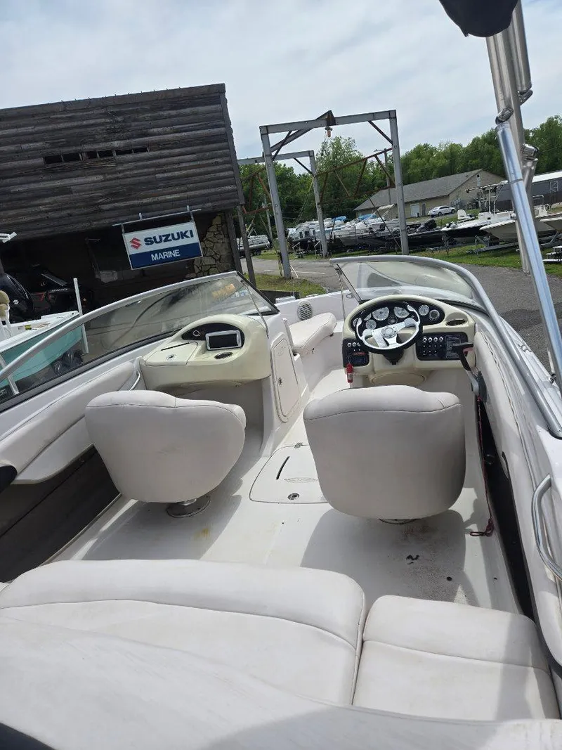 Slide: The Image of 2012 Tahoe Q8 SSi boat interior with white seating and dashboard, parked near Suzuki sign. - 48