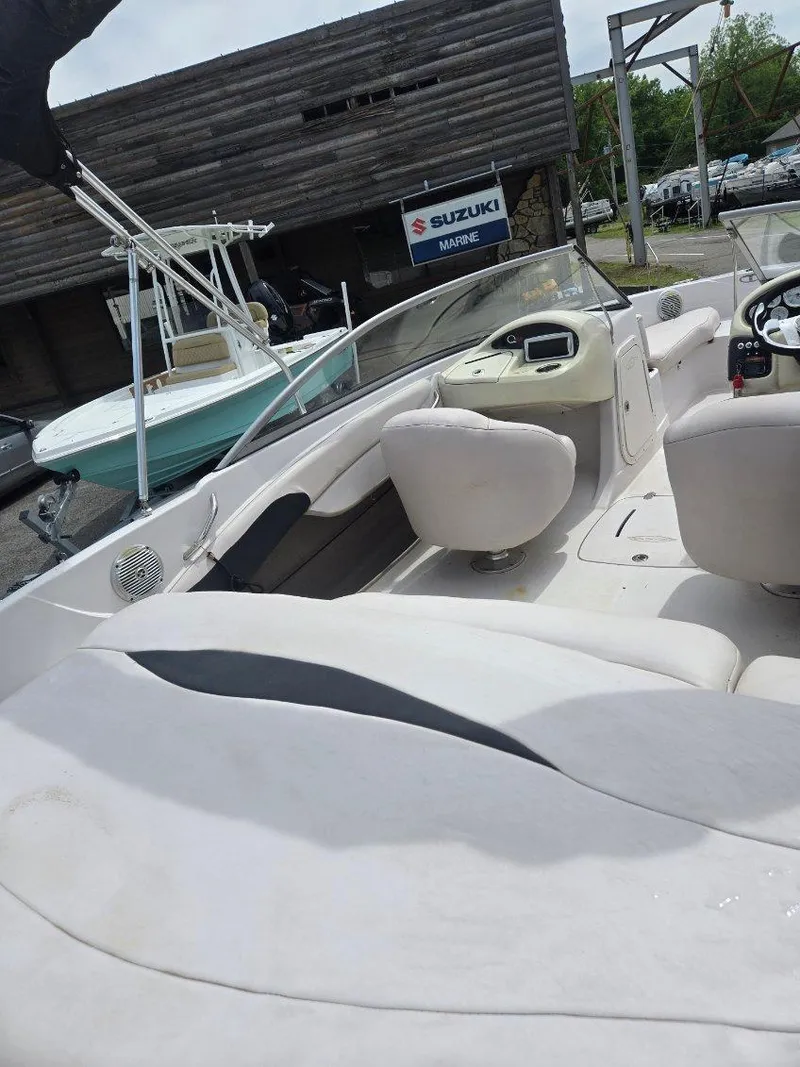 Slide: The Image of 2012 Tahoe Q8 SSi boat interior with white seating, docked near Suzuki Marine sign. - 49