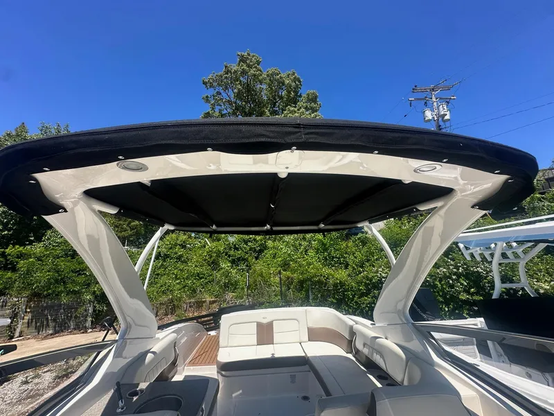 Slide: The Image of 2014 Chaparral 307 SSX boat interior with canopy, featuring seating and clear blue sky. - 14
