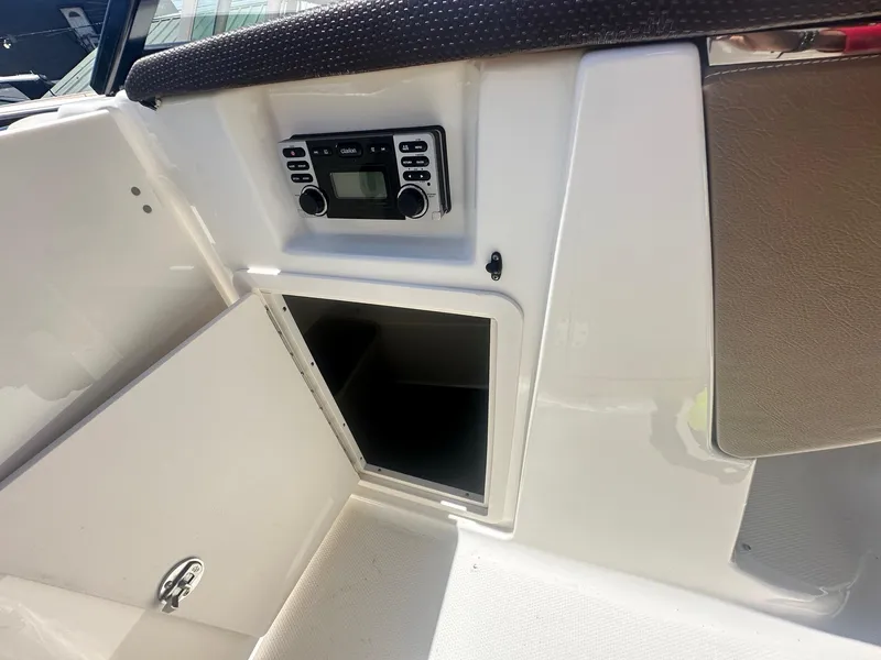 Slide: The Image of 2014 Chaparral 307 SSX boat interior with stereo system and storage compartment. - 25
