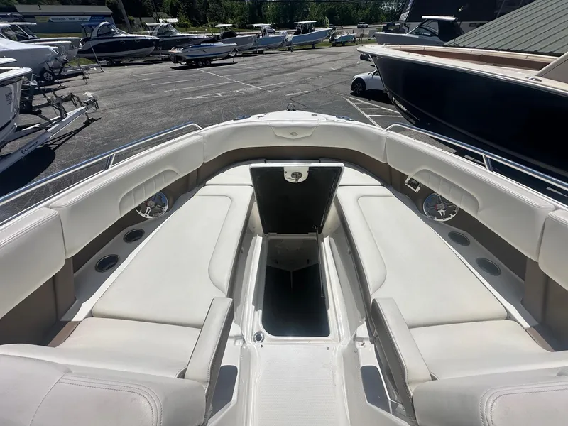 Slide: The Image of 2014 Chaparral 307 SSX boat interior with spacious seating and storage, docked in a marina. - 37