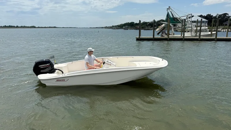 Slide: The Image of 2023 Boston Whaler 160 Super Sport boat on calm water near a dock. - 12