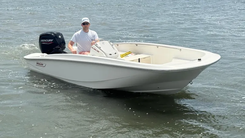 Slide: The Image of 2023 Boston Whaler 160 Super Sport boat on water with driver. - 2