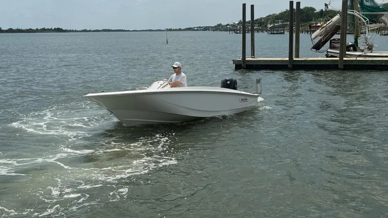 Slide: The Image of 2023 Boston Whaler 160 Super Sport boat cruising on a calm waterway near a dock. - 8