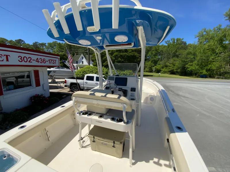 Slide: The Image of 2019 Cobia 220 Center Console boat with T-top, parked near a roadside shop. - 10
