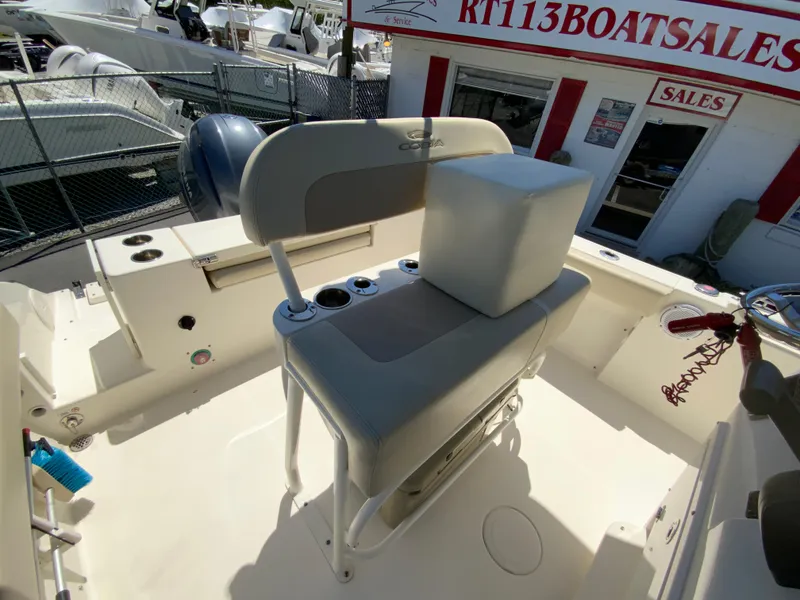Slide: The Image of 2019 Cobia 220 Center Console boat interior at dealership, featuring seating and storage. - 12
