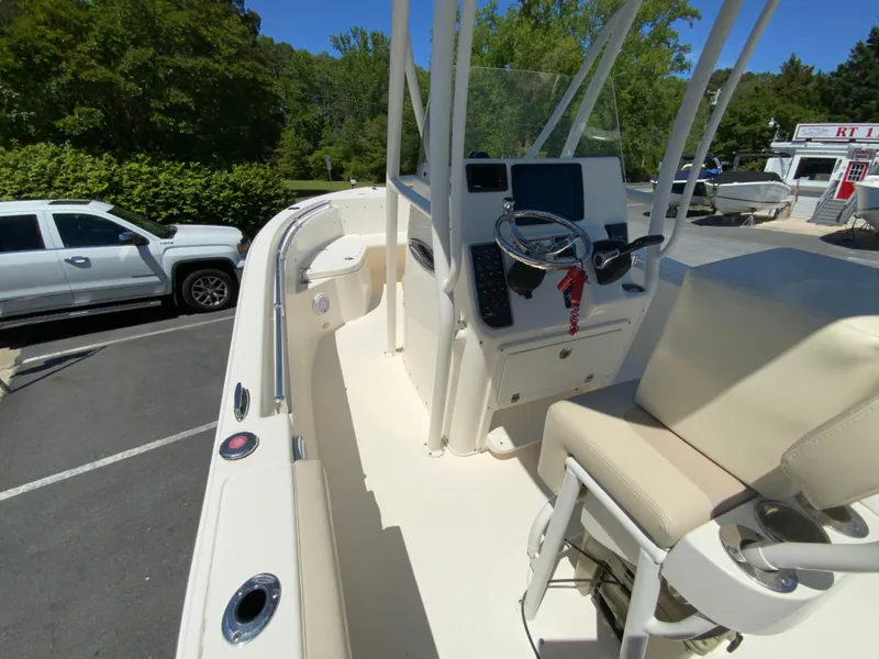 Slide: The Image of 2019 Cobia 220 Center Console boat with steering wheel and seating, parked outdoors. - 16