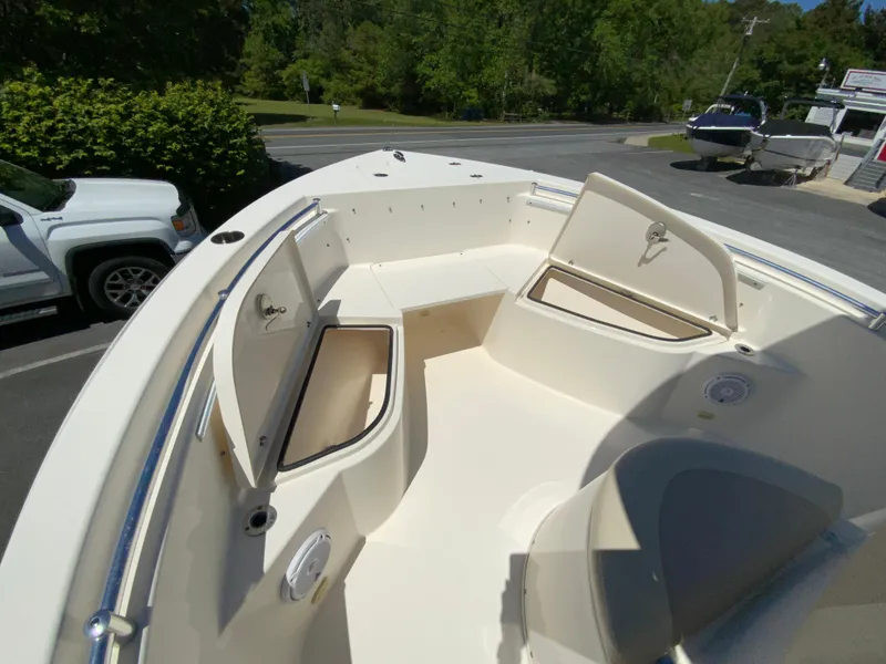 Slide: The Image of 2019 Cobia 220 Center Console boat with open storage compartments, parked outdoors. - 19