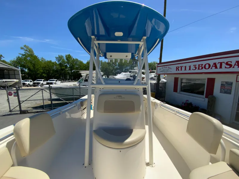 Slide: The Image of 2019 Cobia 220 Center Console boat with blue T-top, docked at a marina. - 23