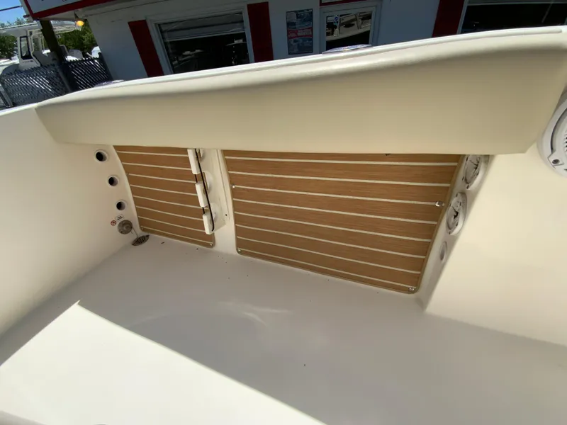 Slide: The Image of 2019 Cobia 220 Center Console boat interior with wooden paneling and seating area. - 27