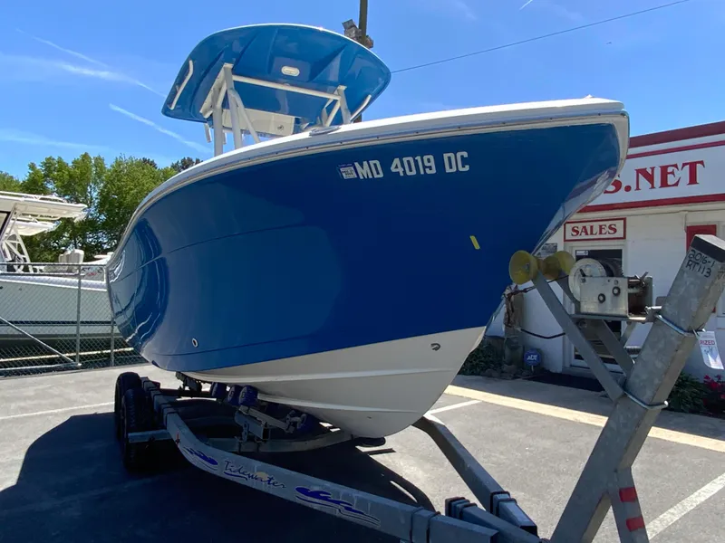 Slide: The Image of 2019 Cobia 220 Center Console boat on trailer, blue hull, parked outdoors. - 3
