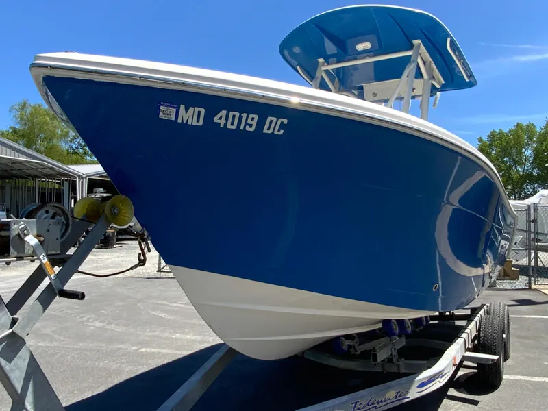 Slide: The Image of 2019 Cobia 220 Center Console boat on trailer, blue hull, parked outdoors. - 4