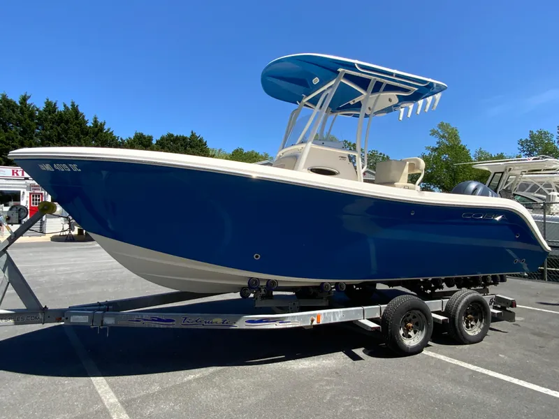 Slide: The Image of 2019 Cobia 220 Center Console boat on trailer, blue hull, parked outdoors. - 5