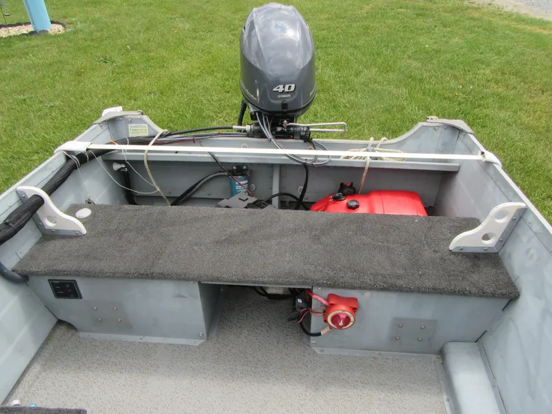 Slide: The Image of 2018 Starcraft SF DLX 16 boat interior with motor and fuel tank on grass. - 19