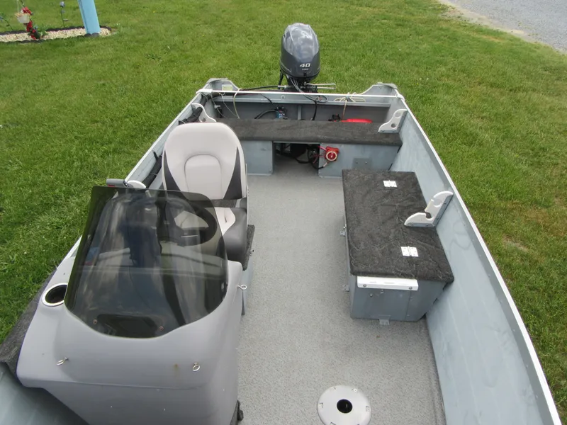 Slide: The Image of 2018 Starcraft SF DLX 16 boat interior with seating and motor, parked on grass. - 6