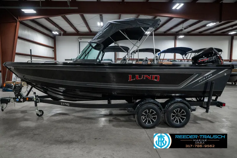 Slide: The Image of 2025 Lund 1975 Tyee boat in showroom, black exterior, on trailer, with canopy. - 10