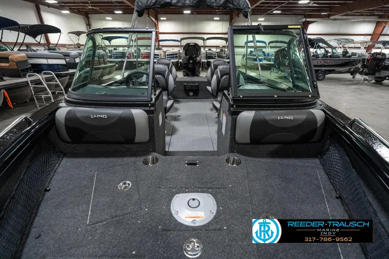 Slide: The Image of 2025 Lund 1975 Tyee boat interior with seating and dashboard, displayed in a showroom. - 18