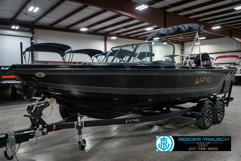 Slide: The Image of 2025 Lund 1975 Tyee boat in showroom, black exterior, on trailer, indoor lighting. - 2