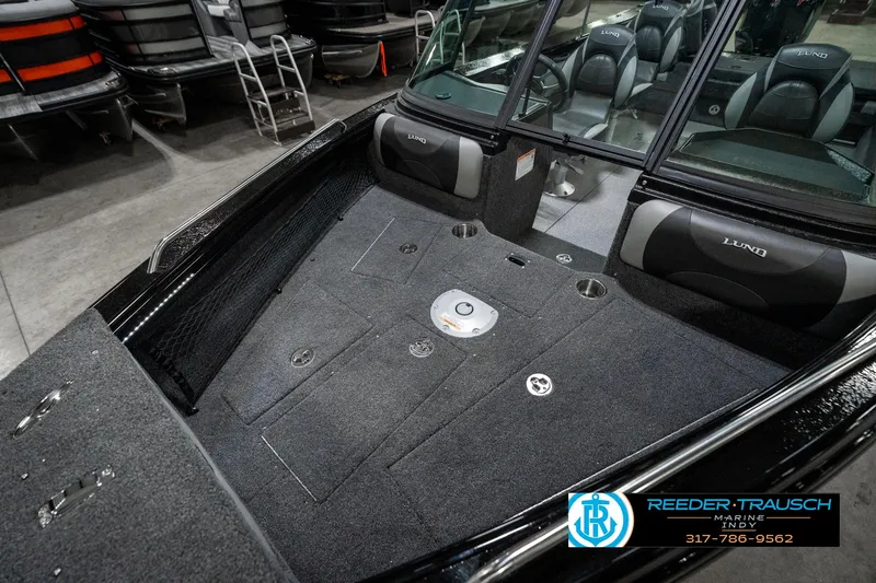 Slide: The Image of 2025 Lund 1975 Tyee boat interior with carpeted deck and seating in showroom. - 21