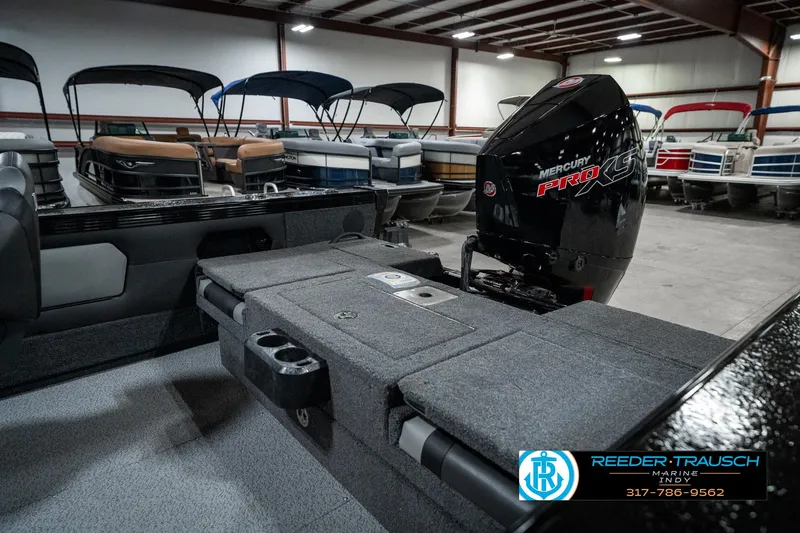 Slide: The Image of 2025 Lund 1975 Tyee boat with Mercury engine in showroom, surrounded by other boats. - 35