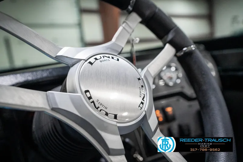 Slide: The Image of Steering wheel of a 2025 Lund 1975 Tyee boat, featuring sleek metallic design. - 42