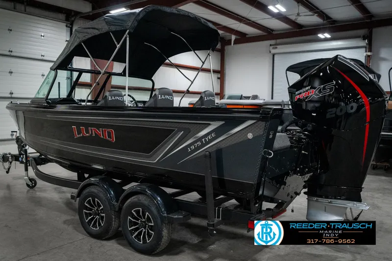 Slide: The Image of 2025 Lund 1975 Tyee boat with canopy and powerful outboard motor in a showroom. - 9
