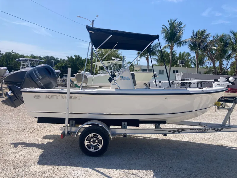 Slide: The Image of 2025 Key West 1720CC boat on trailer, parked outdoors with palm trees in background. - 2