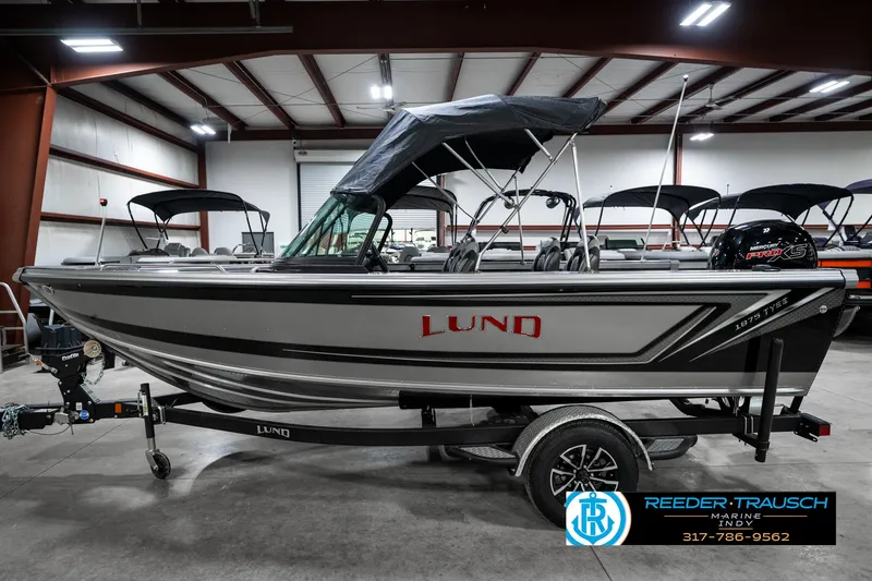 Slide: The Image of 2025 Lund 1875 Tyee boat in showroom, side view with canopy and trailer. - 11