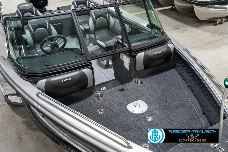 Slide: The Image of 2025 Lund 1875 Tyee boat interior with seating and steering wheel, displayed indoors. - 13