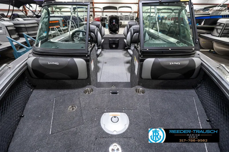Slide: The Image of 2025 Lund 1875 Tyee boat interior with seating and dashboard, displayed in a showroom. - 19