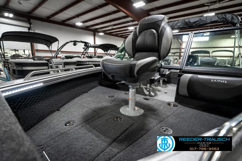 Slide: The Image of 2025 Lund 1875 Tyee boat interior with seating, showcased in a showroom. - 24