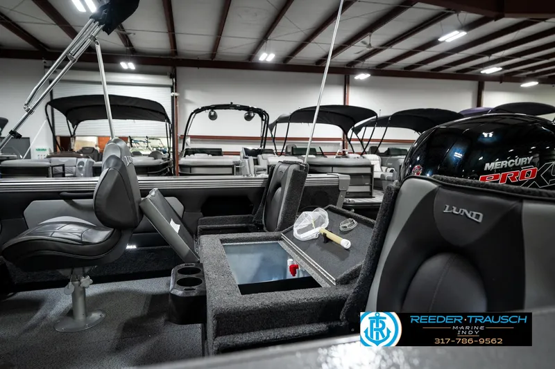 Slide: The Image of 2025 Lund 1875 Tyee boat interior with seating and fishing equipment in showroom. - 36