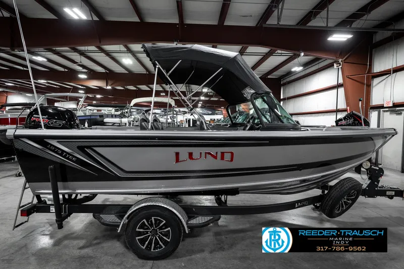 Slide: The Image of 2025 Lund 1875 Tyee boat in showroom, side view with trailer and canopy. - 7