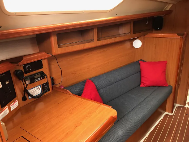 Slide: The Image of 2008 Hunter 31 yacht interior with wooden finish, blue sofa, and red cushions. - 4