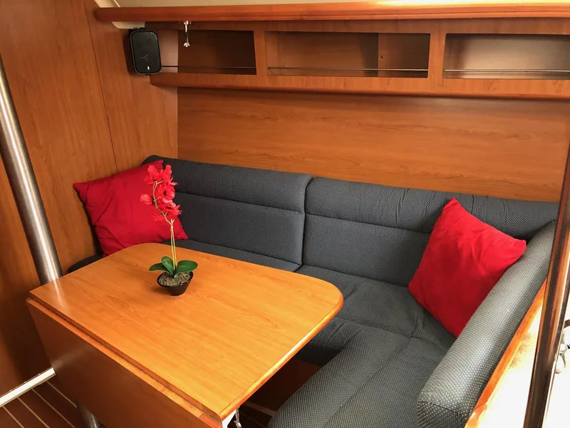 Slide: The Image of Cozy 2008 Hunter 31 yacht interior with wooden table, blue seating, and red cushions. - 5