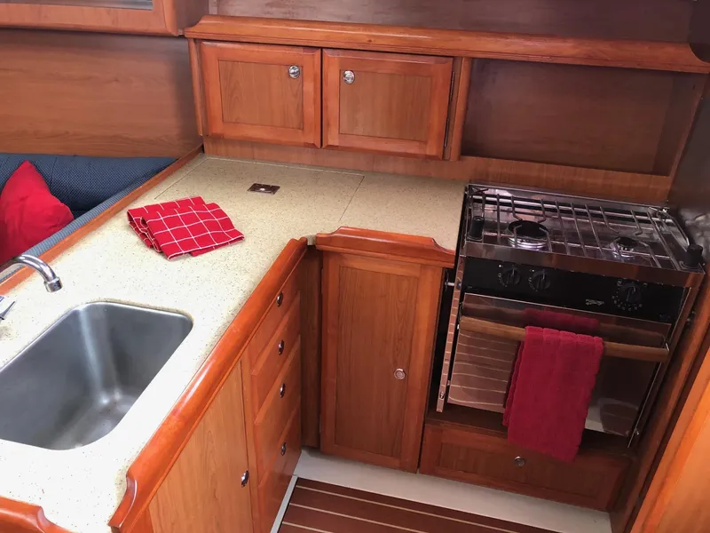 Slide: The Image of 2008 Hunter 31 yacht kitchen with wooden cabinets, sink, and stove. - 9