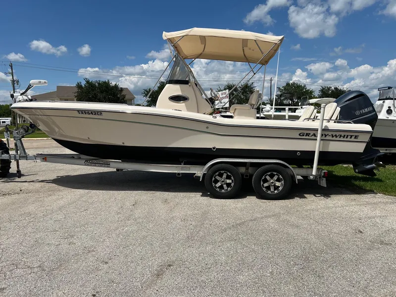 Slide: The Image of 2014 Grady-White 251 Coastal Explorer boat on trailer, parked outdoors under blue sky. - 2