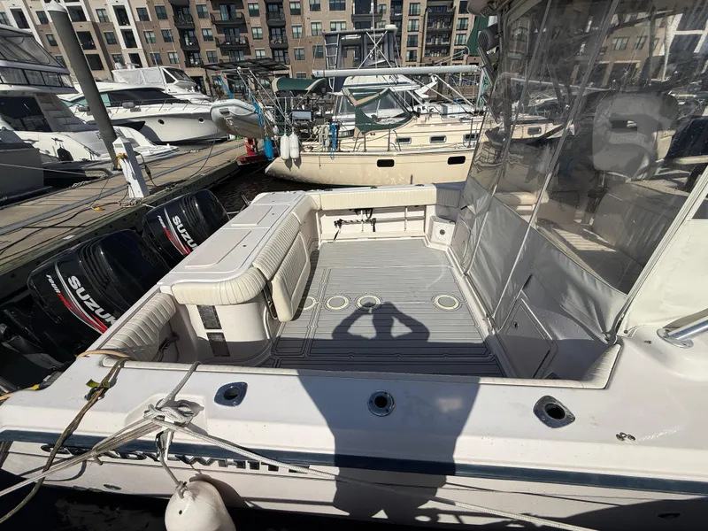 Slide: The Image of 2002 Grady-White Express 330 boat docked, featuring spacious deck and Suzuki outboard engines. - 30