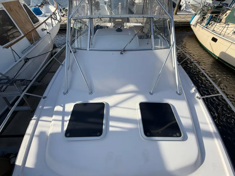 Slide: The Image of 2002 Grady-White Express 330 boat docked, featuring a spacious deck and dual hatches. - 49