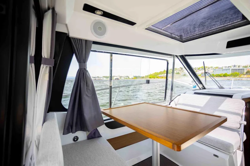 Slide: The Image of Interior of 2022 Jeanneau NC Weekender 895 with dining area and scenic window view. - 14