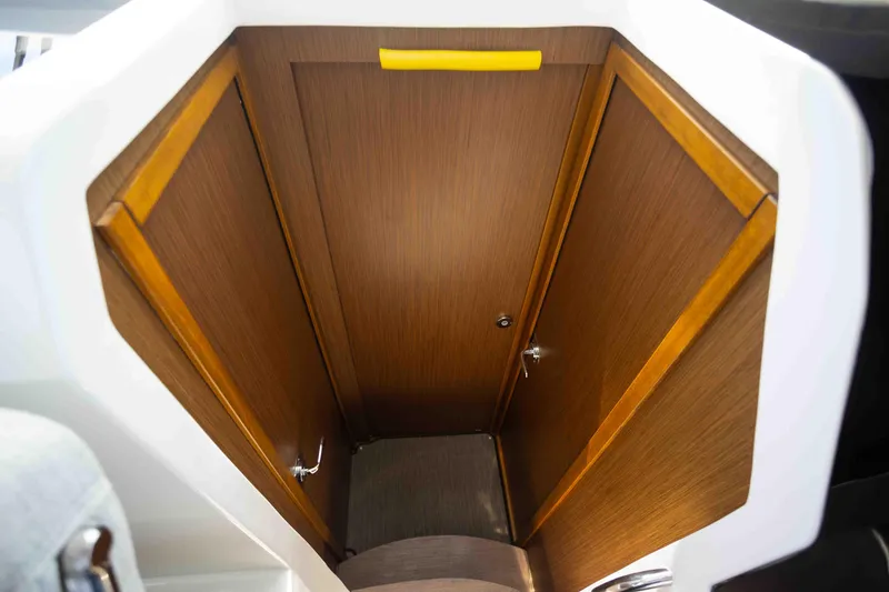 Slide: The Image of 2022 Jeanneau NC Weekender 895 interior storage compartment with wooden finish and yellow handle. - 19