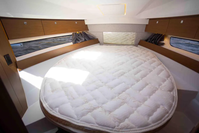 Slide: The Image of 2022 Jeanneau NC Weekender 895 cabin with a spacious round bed and wooden storage cabinets. - 20