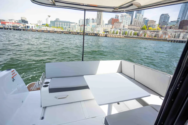 Slide: The Image of 2022 Jeanneau NC Weekender 895 boat with city skyline view, featuring a spacious deck seating area. - 8